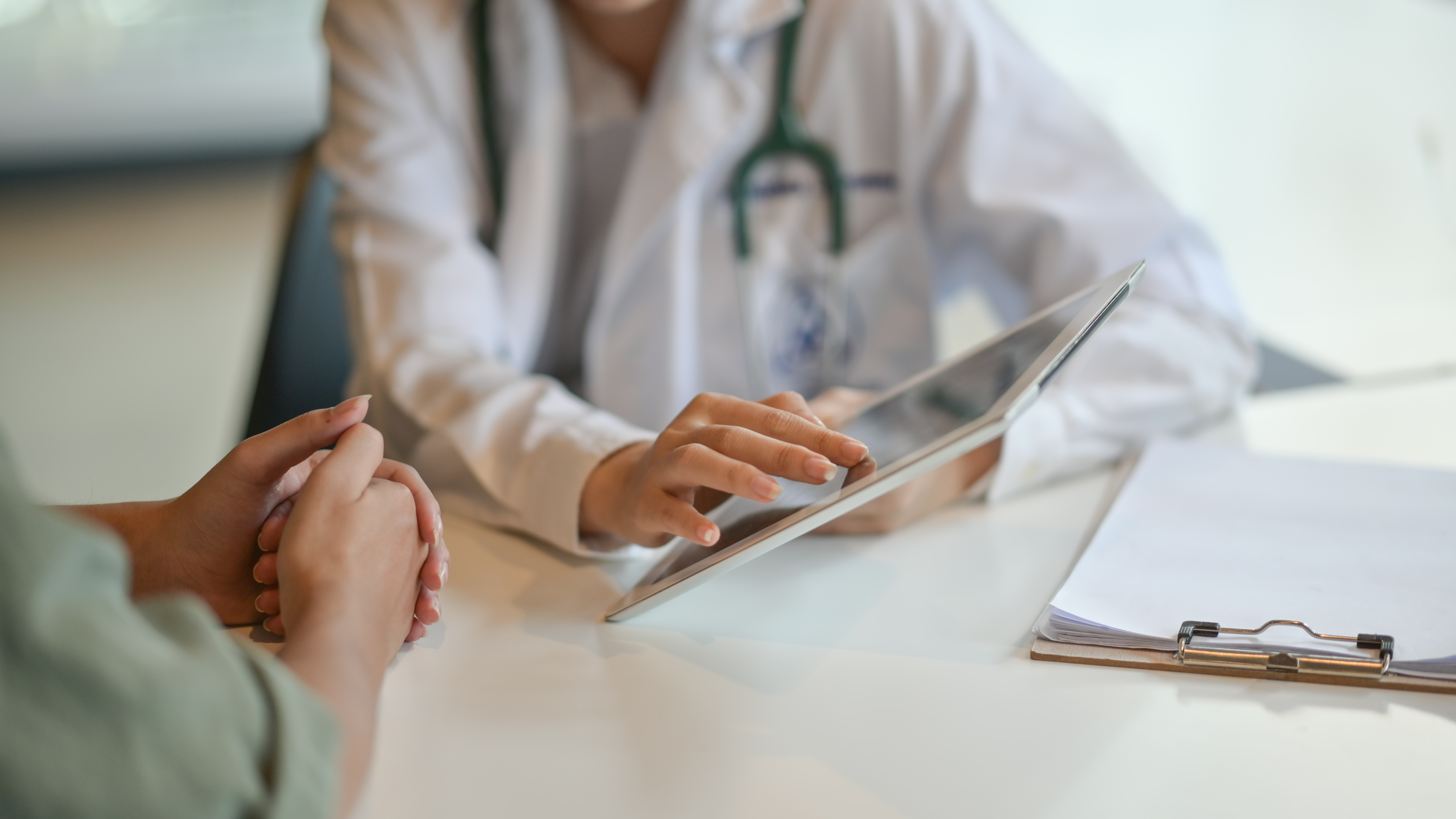 Shot of a doctor in as white lab coat showing a patient off-camera some information on a digital tablet